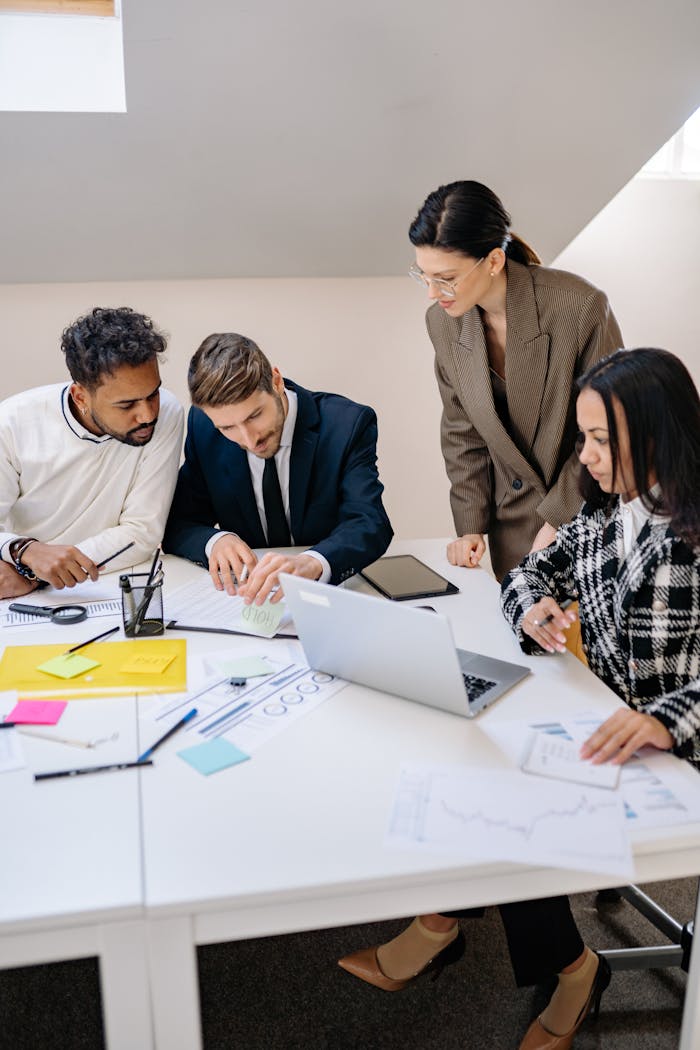 Business team brainstorming ideas at a workspace, using a laptop for planning.
